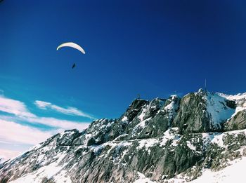 Person parasailing over snowcapped mountain