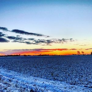 Scenic view of snow covered landscape against sky during sunset