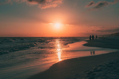 Silhouette people at beach against sky during sunset