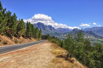 Road amidst plants and mountains against sky