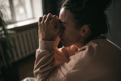 Portrait of woman holding hands on bed at home