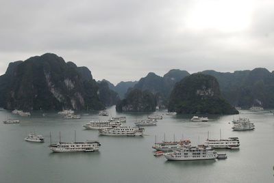 Boats sailing in sea against mountains