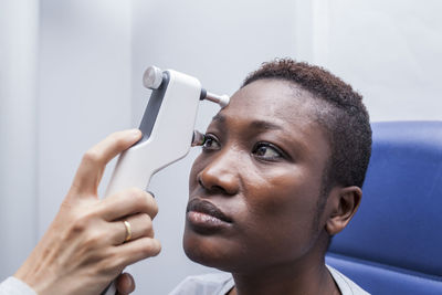 Optometrist using an ophthalmoscope during study of the eyesight of a black woman