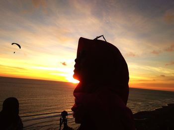 Silhouette man on beach against sky during sunset