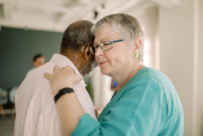 Senior woman with eyes closed dancing with man in class