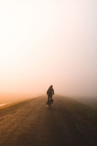 Man riding motorcycle on desert against clear sky