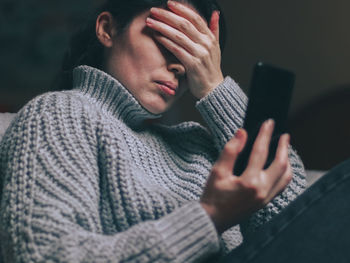 A caucasian young beautiful girl chats online with her friend, covering her face with her palm