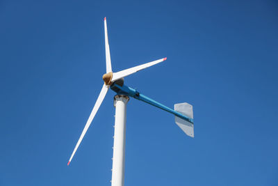 Low angle view of wind turbine against blue sky