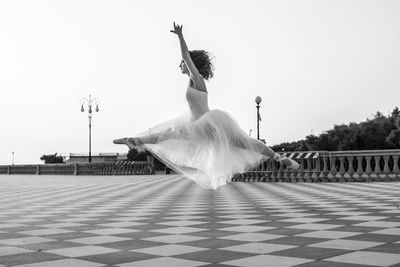 People dancing on tiled floor against clear sky