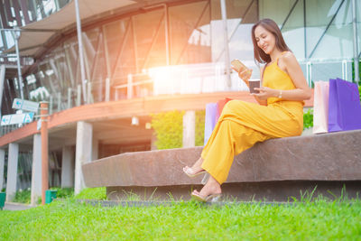 Full length of woman using phone while sitting on grass