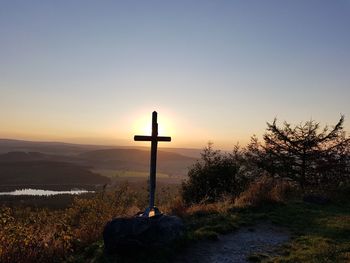 Silhouette cross on field at sunset