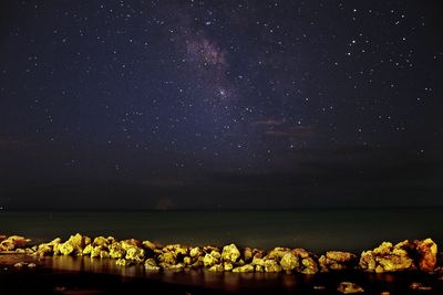 Scenic view of sea against star field at night