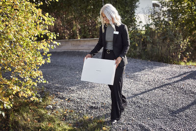 Female estate agent putting for sale sign