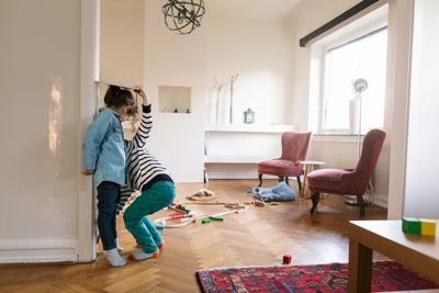 Low section of brother measuring sister's height on wall with book at home