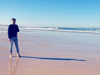 Man standing on beach against clear sky