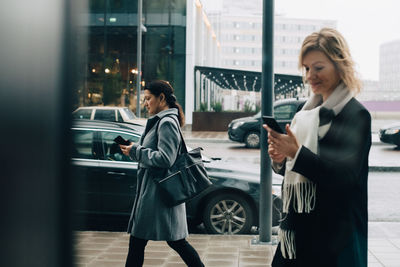 Woman holding camera while standing in city
