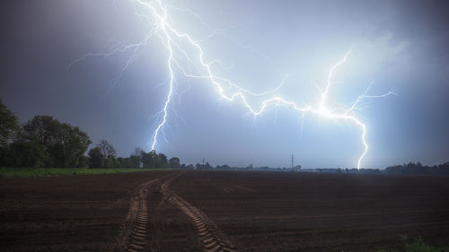 Lightning over landscape against sky at night