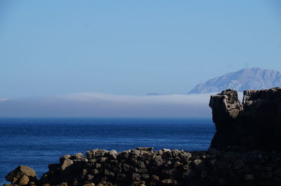 Scenic view of sea and rocks against blue sky