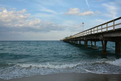 View of fishing pier over sea against sky