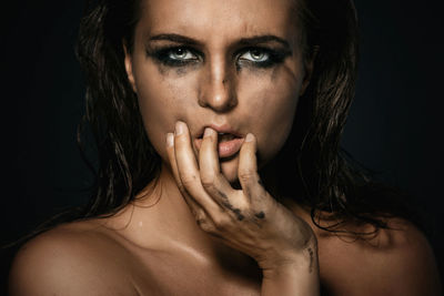 Close-up portrait of young woman against black background