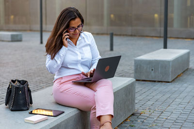 Caucasian business woman with laptop and mobile phone outdoors