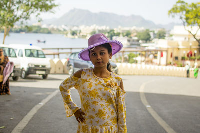 Portrait of cute girl standing on road in city