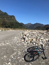 Bicycle on road by mountain against clear blue sky