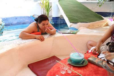 Woman in pool having drink with long drinking straw