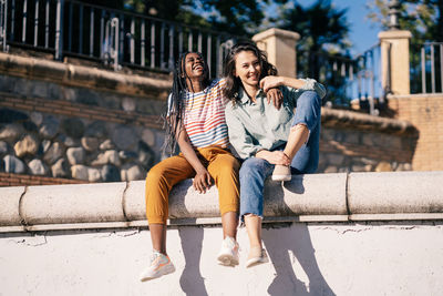 Full length of smiling young women sitting outdoors