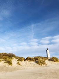 Lighthouse on beach against sky