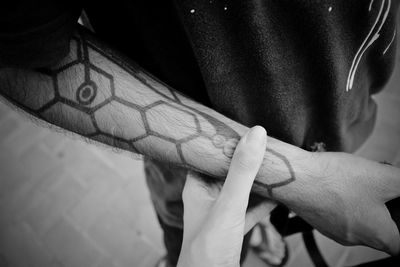 Cropped image of person holding friend hand with tattoo