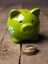 Green piggy bank with coins on wooden table