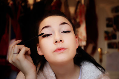 Portrait of teenage girl applying make-up 