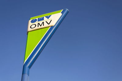 Low angle view of road sign against clear blue sky