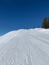 Snow covered land against clear blue sky