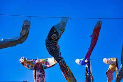 Low angle view of figurines against clear blue sky