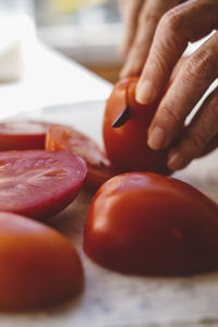 Cropped hands of woman cutting tomatoes on table in kitchen