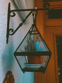 Close-up of electric lamp hanging on wall at home