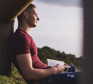 Side view of young man looking at camera