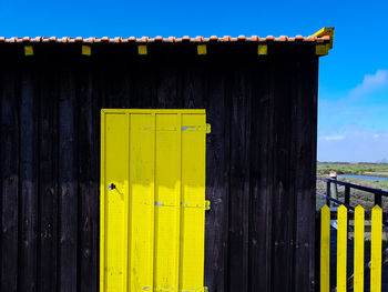 Close-up of yellow metal fence against blue sky