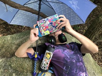 Midsection of woman holding umbrella while sitting on field