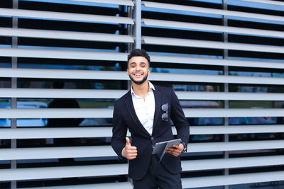 Portrait of smiling businessman holding digital tablet