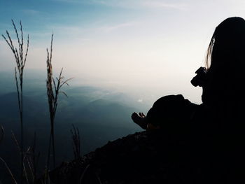 Silhouette man photographing against sky during sunset