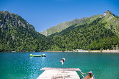 Scenic view of lake and mountains against clear blue sky