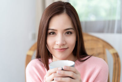 Portrait of woman holding coffee cup at home