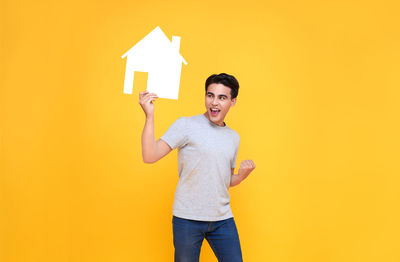 Portrait of a smiling young man against yellow background