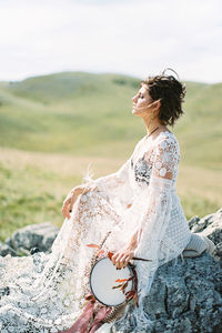 Side view of bride sitting on rock