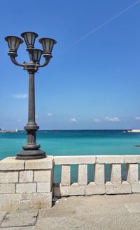 Street light by sea against blue sky