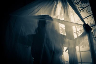 Midsection of woman standing against curtain