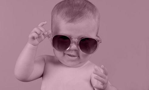 Portrait of boy wearing sunglasses against gray background